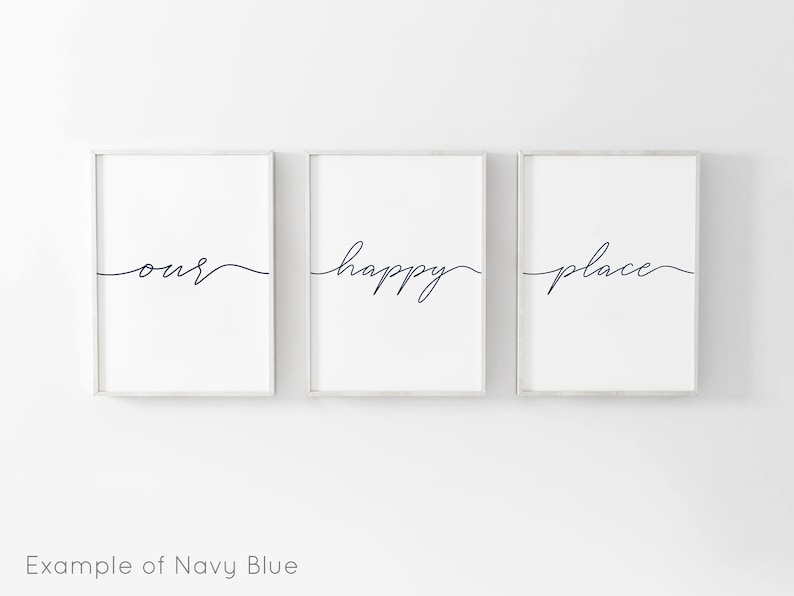 May include: Three framed prints with the words "our", "happy", and "place" written in a cursive script in navy blue. The prints are hung on a white wall.