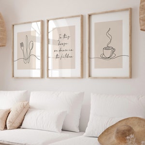 Peut inclure: Trois impressions d'art encadr&eacute;es avec des dessins au trait minimalistes. L'une repr&eacute;sente des couverts, une autre porte le texte "In this house, we dance in the kitchen", et la troisi&egrave;me repr&eacute;sente une tasse &agrave; caf&eacute;. Les impressions ont une palette de couleurs neutres.