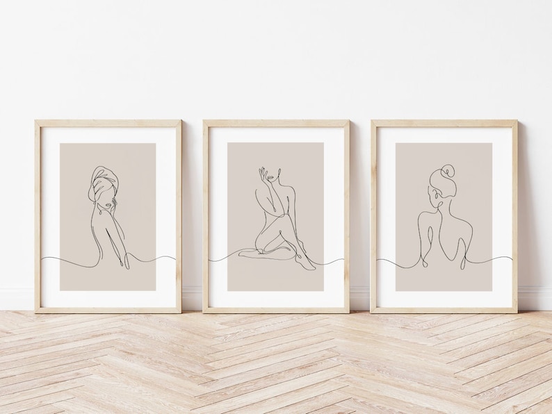 May include: Set of three minimalist line art prints featuring a woman in different poses. The prints are framed in natural wood frames and have a beige background.
