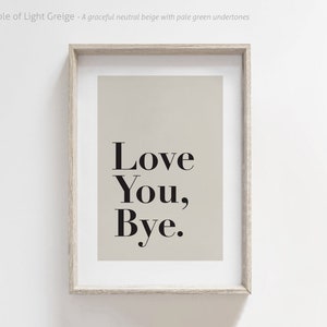 May include: A framed print with a light beige background and black text that reads "Love You, Bye."
