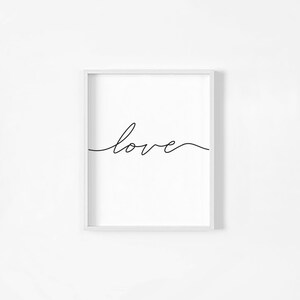 May include: A white framed print with the word "love" written in black cursive script.