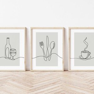 May include: Three minimalist line art prints in wooden frames. The prints depict a wine bottle and glass, a fork, knife, and spoon, and a steaming cup of coffee.