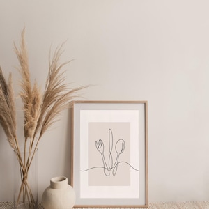 May include: A framed print featuring a minimalist line drawing of a fork, knife, and spoon on a light brown background. The print is in a wooden frame and is resting on a woven rug.
