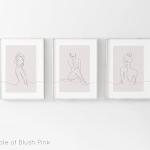 May include: Three framed prints with a blush pink background and black line drawings of women in various poses.