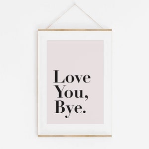 May include: A white framed print with a light pink background and black text that reads "Love You, Bye."