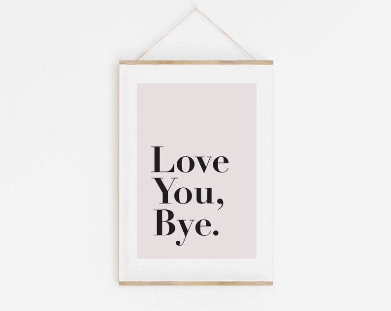 May include: A white framed print with a light pink background and black text that reads "Love You, Bye."