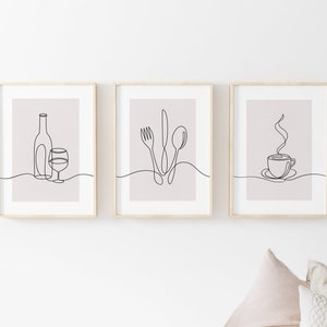 May include: Three minimalist line art prints in wooden frames. The prints depict a wine bottle and glass, a fork, knife, and spoon, and a steaming cup of coffee.