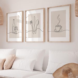 May include: Three minimalist line art prints in wooden frames. The prints feature a bottle of wine and a glass, a fork, knife, and spoon, and a steaming cup of coffee.