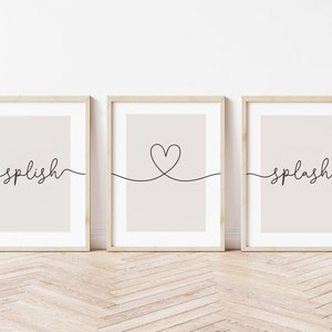 May include: Three framed prints with a minimalist design. The left print features the word "splish" in cursive script. The middle print features a simple heart shape drawn with a single line. The right print features the word "splash" in cursive script.