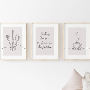 Peut inclure: Trois impressions encadr&eacute;es avec des dessins au trait. L'une repr&eacute;sente des couverts : une fourchette, un couteau et une cuill&egrave;re. Une autre porte le texte "In this house, we dance in the kitchen." La troisi&egrave;me montre une tasse de caf&eacute;.