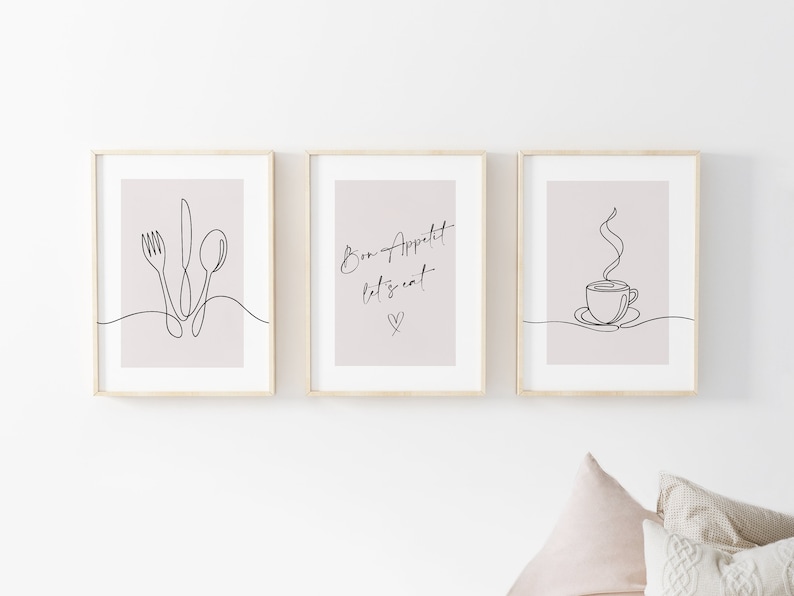 K&ouml;nnte beinhalten: Drei gerahmte Kunstdrucke mit minimalistischen Strichzeichnungen. Einer zeigt eine Gabel, ein Messer und einen L&ouml;ffel, ein anderer sagt "Bon Appetit let's eat" mit einem Herzen, und der dritte zeigt eine dampfende Kaffeetasse. Die Rahmen sind aus hellem Holz, der Hintergrund ist hellbeige.