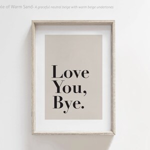 May include: A framed print with a beige background and black text that reads "Love You, Bye."