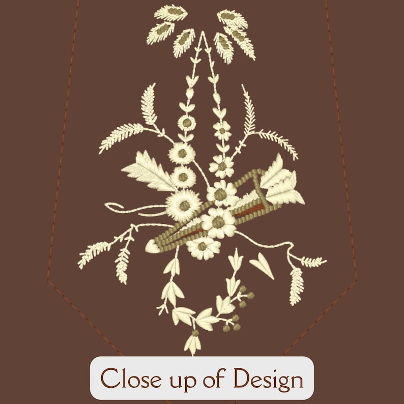 May include: A brown fabric background with a white embroidered design of a floral bouquet with a small brown object in the centre. The design is in the shape of a heart.