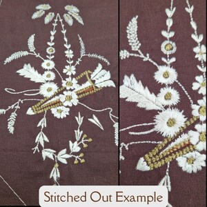 May include: Close-up of a brown fabric with white embroidery of a floral design. The design includes a basket with arrows, flowers, and leaves. The embroidery is stitched out, meaning it is raised from the fabric.