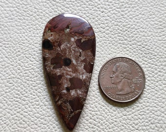 May include: A teardrop-shaped cabochon of brown, white, and black jasper with a polished surface. The stone is about the size of a US quarter.