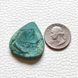 May include: A green malachite guitar pick shaped like a triangle. The pick is about the size of a US quarter.