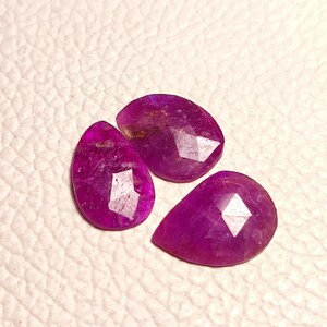 May include: Three faceted purple gemstone drops. The gemstones are cut in a teardrop shape and have a shiny, polished finish.