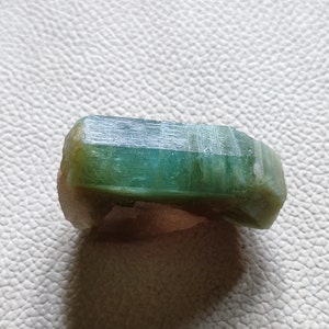 Könnte beinhalten: Ein grüner Aquamarin-Kristall mit einer glatten, polierten Oberfläche. Der Kristall hat eine rechteckige Form und ist durchscheinend.