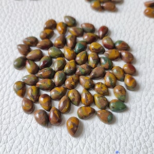 May include: A collection of approximately 40 teardrop-shaped, polished stones with a mix of brown, green, and yellow colours. The stones have a mottled, marbled appearance.