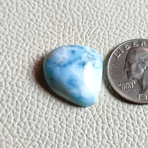 Op de afbeelding: Een hartvormige blauwe en witte edelsteen met een marmerpatroon. De edelsteen is ongeveer zo groot als een Amerikaanse kwart.