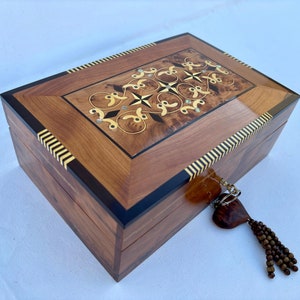 May include: A wooden box with a decorative inlay of wood and mother of pearl. The box has a heart-shaped keyhole with a tassel.