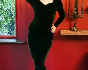 Un elegante vestido de tubo de terciopelo verde único en su clase con escote corazón y mangas largas.