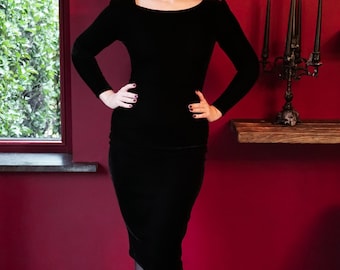 Un elegante vestido de tubo de terciopelo negro con escote barco y mangas largas.