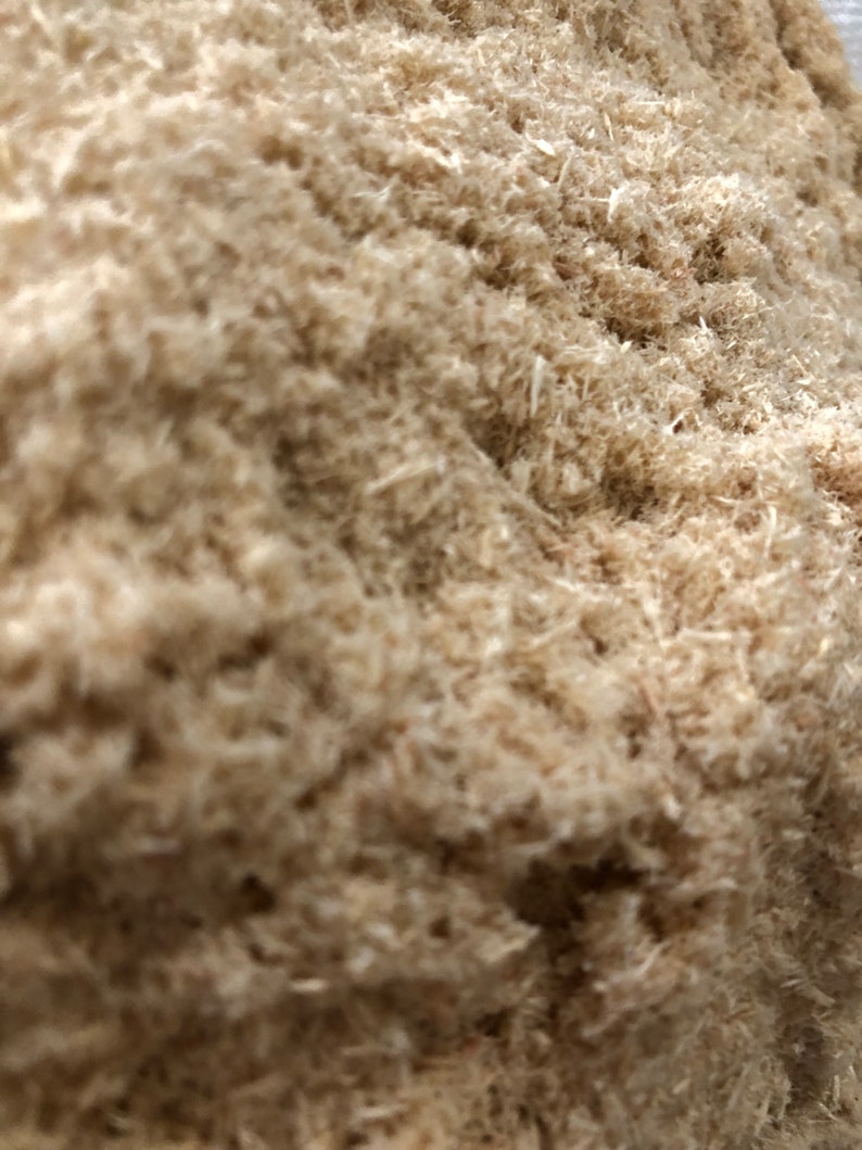 May include: A close-up of a pile of wood shavings. The shavings are light brown and have a soft, fluffy texture.
