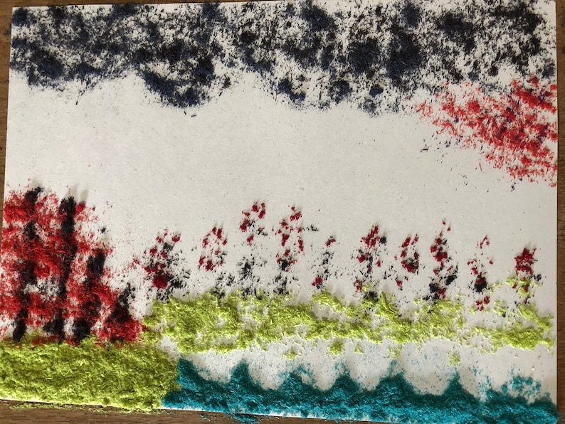 May include: A white background with a blue, red, and green sand art design. The design features a row of trees with red and black sand, a green grassy area, and a blue wavy line representing water.