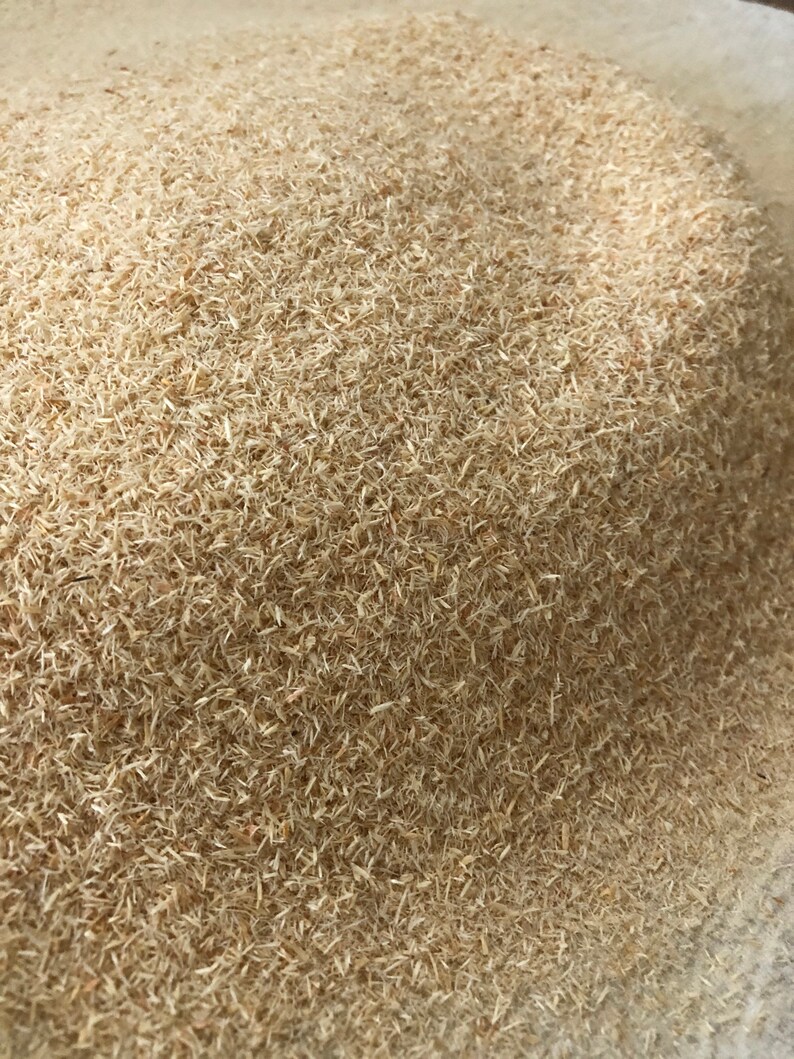 May include: A close-up of a pile of light brown wood shavings. The shavings are very fine and appear to be made from softwood.