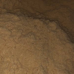 May include: Close-up of a pile of brown wood shavings. The shavings are fine and fluffy, creating a soft, textured surface.