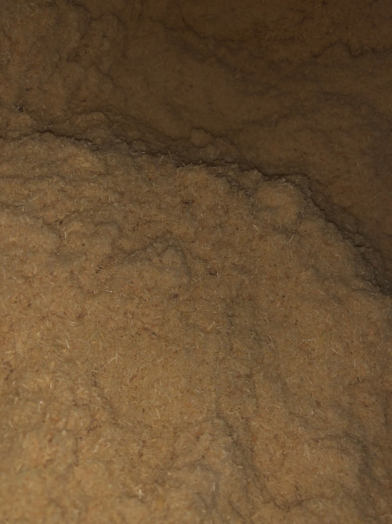 May include: Close-up of a pile of brown wood shavings. The shavings are fine and fluffy, creating a soft, textured surface.