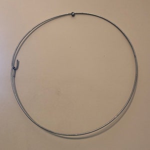 May include: A silver metal hoop with a small ball at the top and a hook on the side.