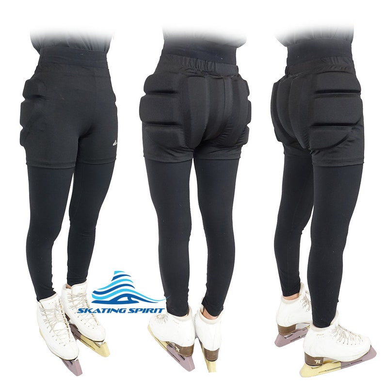 May include: Black figure skating pants with padded hips and a logo that says "SKATING SPIRIT". The pants are worn by a person wearing white figure skates.