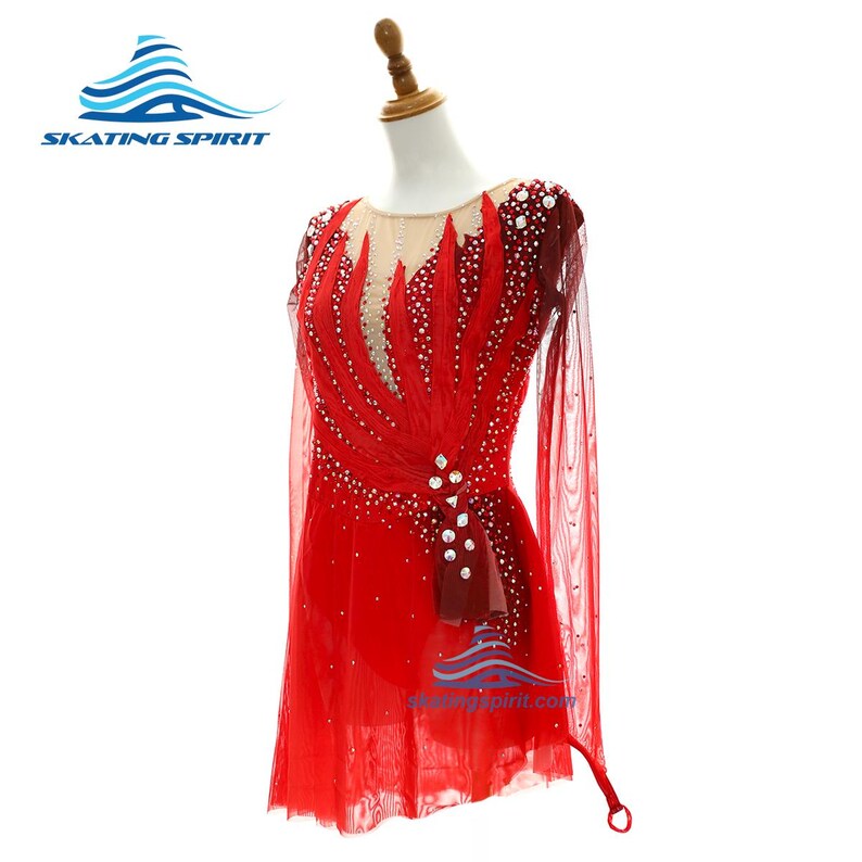 Peut inclure: Une robe de patinage artistique rouge &agrave; manches longues avec un haut transparent couleur chair, des superpositions de tissu rouge en forme de flammes et des cristaux transparents. La tenue comprend une jupe &eacute;vas&eacute;e et des manches longues.