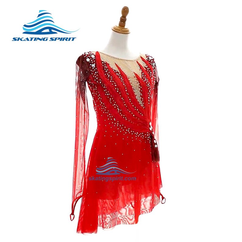 Peut inclure: Une robe de patinage rouge &agrave; manches longues avec une encolure en maille beige transparente, des motifs de flammes complexes et des cristaux clairs dispers&eacute;s. La tenue comprend une jupe superpos&eacute;e et le logo Skating Spirit.