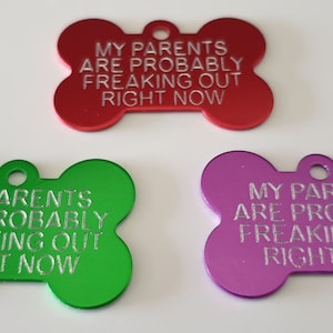 May include: Three dog bone-shaped tags with the text "My parents are probably freaking out right now" engraved on them. The tags are red, green, and purple.