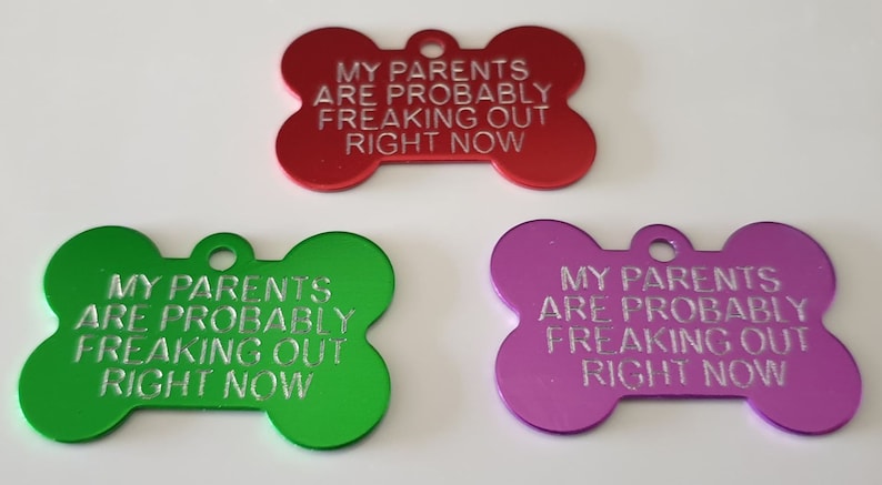 May include: Three dog bone-shaped tags with the text "My parents are probably freaking out right now" engraved on them. The tags are red, green, and purple.