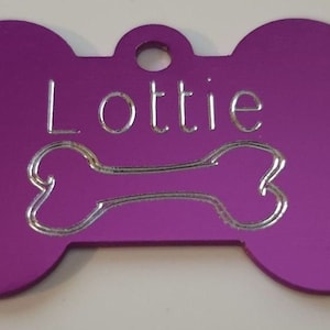 May include: Purple bone-shaped dog tag with the name "Lottie" engraved in silver lettering.