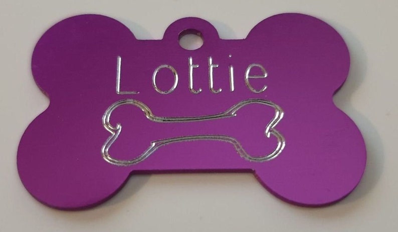 May include: Purple bone-shaped dog tag with the name "Lottie" engraved in silver lettering.