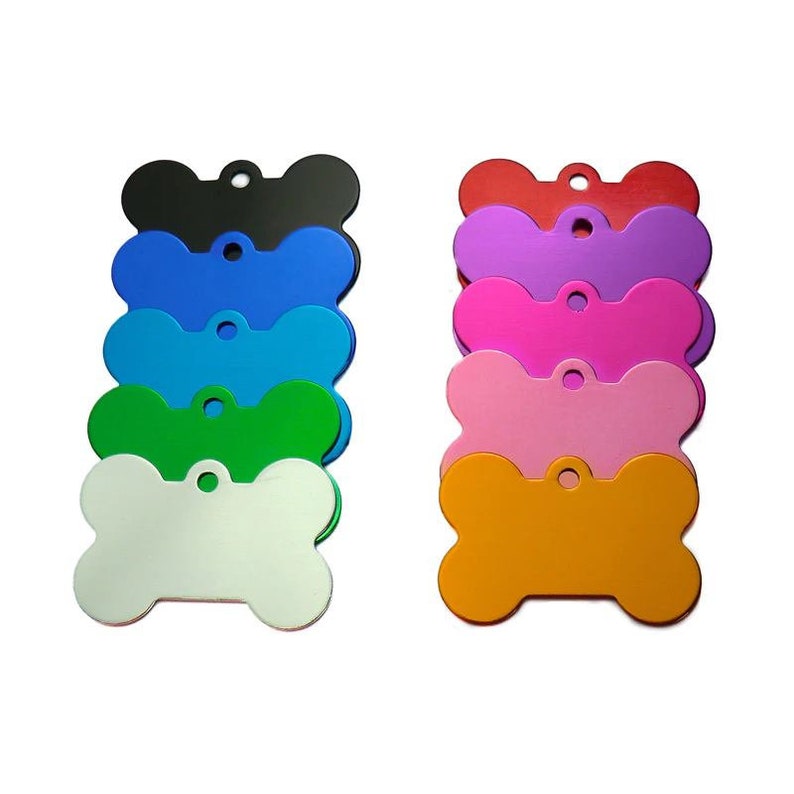 May include: A set of ten blank dog bone-shaped metal tags in various colors, including black, blue, green, white, pink, purple, red, and orange. The tags are all the same size and shape, and they have a hole at the top for attaching a leash or collar.