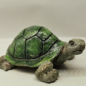Pode incluir: Uma pequena figura de tartaruga verde com uma casca detalhada e um acabamento texturizado e pintado.