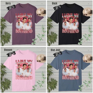 May include: Four different color t-shirts with a graphic print of a group of men with the text "I Love My Boyfriend" in red and white letters. The t-shirts are available in berry, black, blossom, and blue jean.