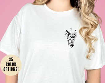 May include: White t-shirt with a black and white graphic of a hand holding scissors and a comb, with the text "Hair Hustler".