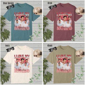 May include: Four t-shirts in different colors with a graphic print of a group of men with the text "I Love My Boyfriend" and "With All My Heart" printed on the front.