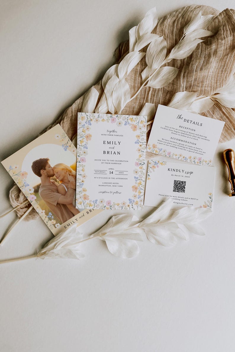 May include: Wedding invitation suite featuring floral accents and the names "Emily and Brian." The suite includes an invitation, details card, RSVP card, and a photo card. The design is soft and romantic, with a neutral color palette and delicate floral borders.