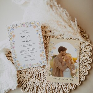 May include: Wedding invitation suite featuring floral designs. The invitation includes the names "Emily and Brian", date, time, and location. A photo card shows a couple embracing, also with the names "Emily and Brian".