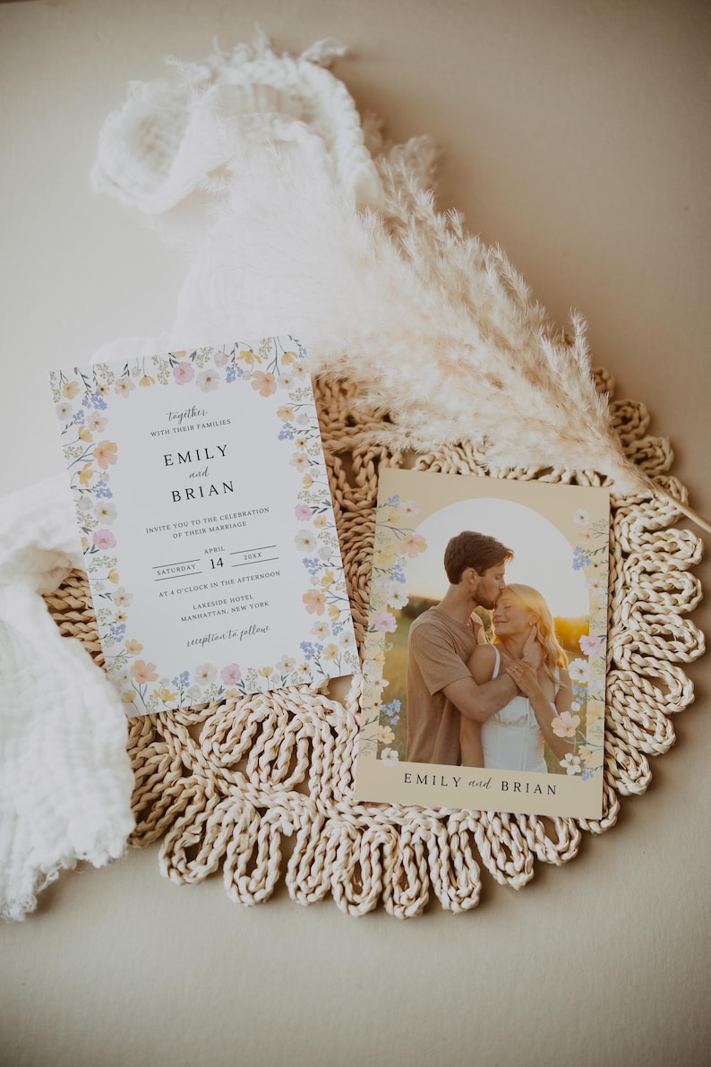May include: Wedding invitation suite featuring floral designs. The invitation includes the names "Emily and Brian", date, time, and location. A photo card shows a couple embracing, also with the names "Emily and Brian".