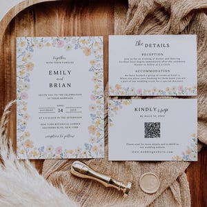 May include: Wedding invitation suite with floral border. Includes invitation, details, and RSVP cards. The invitation reads "Emily and Brian" and "New York Botanical Garden." A gold wax seal and stamp are also present.