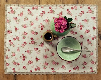 Set of two coated placemats with small red roses in a cotton polyester blend that is easy to wipe clean, hand-crafted with a lace border